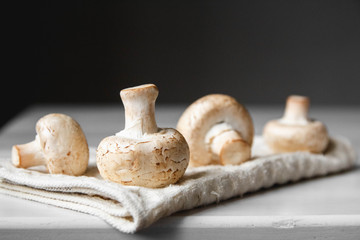 Mushrooms champignons on the kitchen napkin on a white wooden table. Place for text or advertising