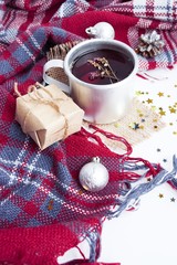 Hot christmas beverage black tea with thyme in mug with new year decorations, Cone, present, silver ball, plaid on white background. Winter time top view.