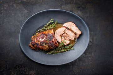 Gegrillter marinierter griechischer Lammbraten mit Kräuter in Braten Sauce als Draufsicht auf einem Modern Design Teller mit Textfreiraum