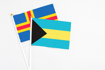 Bahamas and Aland Islands stick flags on white background. High quality fabric, miniature national flag. Peaceful global concept.White floor for copy space.