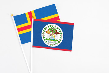 Belize and Aland Islands stick flags on white background. High quality fabric, miniature national flag. Peaceful global concept.White floor for copy space.
