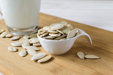 close-up, pumpkin seeds and glass of pumpkin milk on wooden background