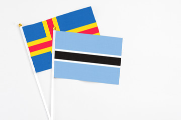 Botswana and Aland Islands stick flags on white background. High quality fabric, miniature national flag. Peaceful global concept.White floor for copy space.