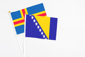 Bosnia Herzegovina and Aland Islands stick flags on white background. High quality fabric, miniature national flag. Peaceful global concept.White floor for copy space.
