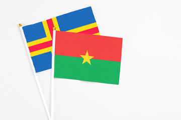 Burkina Faso and Aland Islands stick flags on white background. High quality fabric, miniature national flag. Peaceful global concept.White floor for copy space.