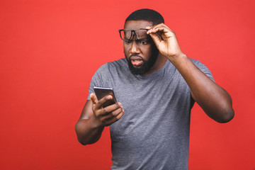 Young african american man using smartphone stressed, shocked with shame and surprise face, angry...