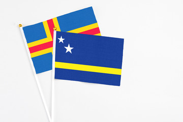 Curacao and Aland Islands stick flags on white background. High quality fabric, miniature national flag. Peaceful global concept.White floor for copy space.