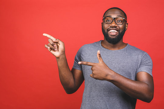Afro american man over isolated red background amazed and smiling to the camera while presenting with hand and pointing with finger.