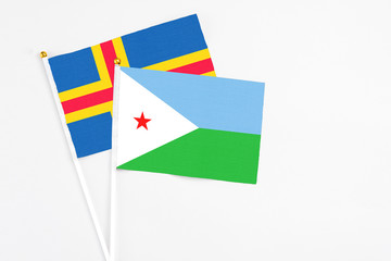 Djibouti and Aland Islands stick flags on white background. High quality fabric, miniature national flag. Peaceful global concept.White floor for copy space.