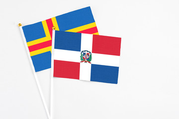 Dominican Republic and Aland Islands stick flags on white background. High quality fabric, miniature national flag. Peaceful global concept.White floor for copy space.