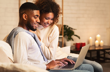 Young married couple using laptop at cozy winter evening