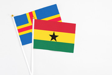 Ghana and Aland Islands stick flags on white background. High quality fabric, miniature national flag. Peaceful global concept.White floor for copy space.