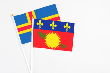 Guadeloupe and Aland Islands stick flags on white background. High quality fabric, miniature national flag. Peaceful global concept.White floor for copy space.