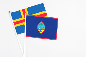 Guam and Aland Islands stick flags on white background. High quality fabric, miniature national flag. Peaceful global concept.White floor for copy space.