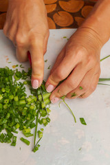 Cutting fresh greens and green onions on a white cutting Board