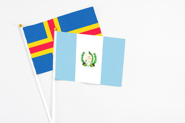 Fototapeta na wymiar Guatemala and Aland Islands stick flags on white background. High quality fabric, miniature national flag. Peaceful global concept.White floor for copy space.