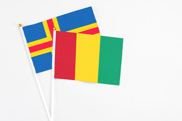 Guinea and Aland Islands stick flags on white background. High quality fabric, miniature national flag. Peaceful global concept.White floor for copy space.