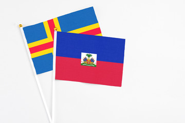Haiti and Aland Islands stick flags on white background. High quality fabric, miniature national...