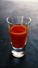 Tomato juice in a vodka glass on black concrete