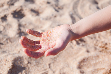 Children's hand in the sand. Yellow sand on the beach
