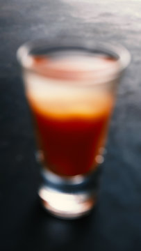 Blurred image of a glass of vodka with red juice
