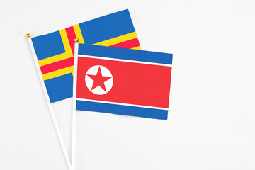 North Korea and Aland Islands stick flags on white background. High quality fabric, miniature national flag. Peaceful global concept.White floor for copy space.