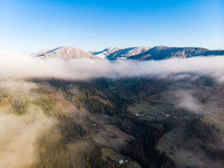 Aeril View fog in the mountains the background of peaks with snow in the autumn in Carpathians.