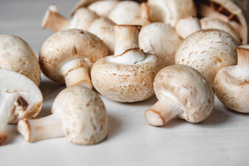 Mushrooms champignons in paper bag on a white wooden table. Place for text or advertising. Top view