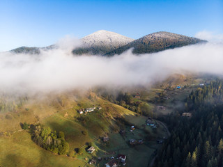 Aeril View fog in the mountains the background of peaks with snow in the autumn in Carpathians.