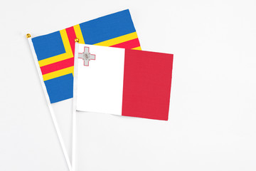 Malta and Aland Islands stick flags on white background. High quality fabric, miniature national flag. Peaceful global concept.White floor for copy space.