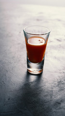 Tomato juice in a vodka glass on black concrete
