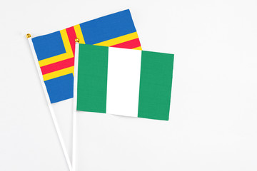 Nigeria and Aland Islands stick flags on white background. High quality fabric, miniature national flag. Peaceful global concept.White floor for copy space.