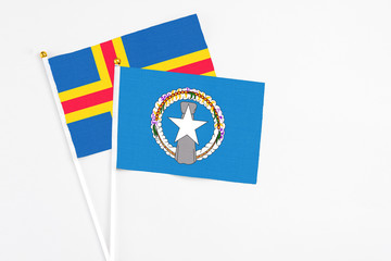 Northern Mariana Islands and Aland Islands stick flags on white background. High quality fabric, miniature national flag. Peaceful global concept.White floor for copy space.