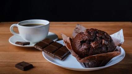Delicious Chocolate muffin, Chocolate and cup of black coffee on the table.