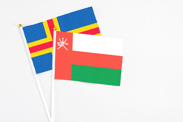 Oman and Aland Islands stick flags on white background. High quality fabric, miniature national flag. Peaceful global concept.White floor for copy space.