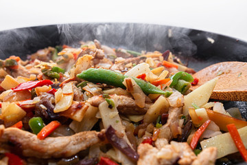 Frying vegetables and meat in hot cast iron skillet, hot and steamy