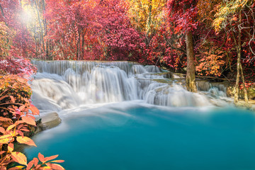 The beautiful autumn have smooth flowing blue waterfall and gold sunlight flare and many red tree and yellow tree at huay-mae-kamin-waterfall kanchanaburi in thailand., place popular on holiday
