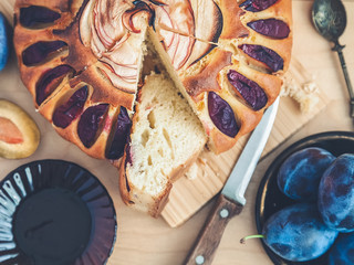 still life: a round plum cake, cut into pieces, decorated with a rose from apple slices, a saucer with fruit