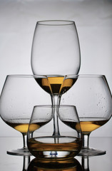 Wine glass goblets on short legs. Nearby is a glass on a long leg and a glass for whiskey. There is a small amount of alcohol in the glasses.