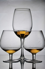 Wine glass goblets on short legs. Nearby is a glass on a long leg. They have a small amount of alcohol.