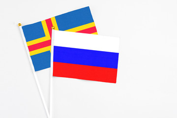 Russia and Aland Islands stick flags on white background. High quality fabric, miniature national flag. Peaceful global concept.White floor for copy space.