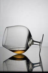 Short-stemmed wine glass. Lies on its side, photographed in the light. It has a small amount of alcohol.