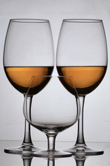 Wine glass goblets on long legs. They have a small amount of alcohol. Nearby is a glass on a short leg.