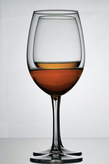 Wine glass goblets on a long leg. They stand one by one. They have a small amount of alcohol.