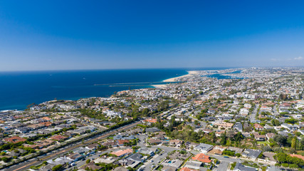 Aerial drone shot over Newport Beach in Orange County, California with coastal neighborhoods on blue sky sunny day.