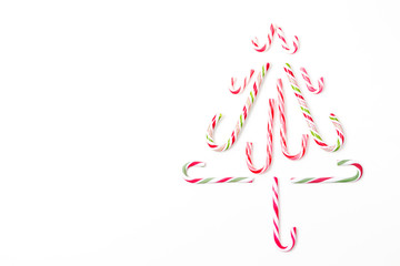 Obraz na płótnie Canvas Christmas tree shape made of candy canes on white background. Top view