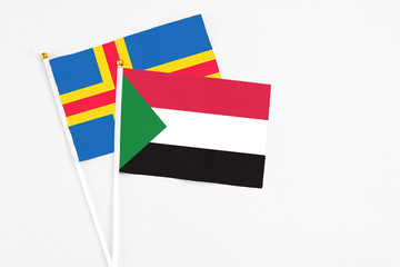 Sudan and Aland Islands stick flags on white background. High quality fabric, miniature national flag. Peaceful global concept.White floor for copy space.