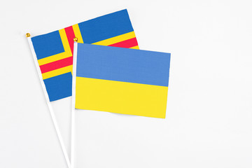 Ukraine and Aland Islands stick flags on white background. High quality fabric, miniature national flag. Peaceful global concept.White floor for copy space.