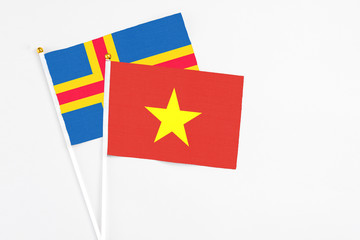Vietnam and Aland Islands stick flags on white background. High quality fabric, miniature national flag. Peaceful global concept.White floor for copy space.