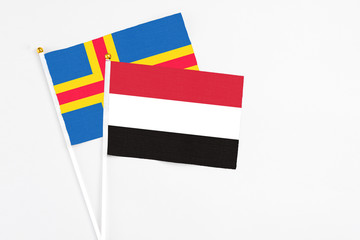 Yemen and Aland Islands stick flags on white background. High quality fabric, miniature national flag. Peaceful global concept.White floor for copy space.